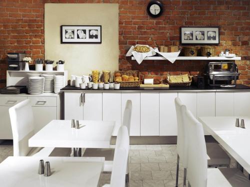 a restaurant with white tables and a counter with food at Ibis Styles Stockholm Odenplan in Stockholm