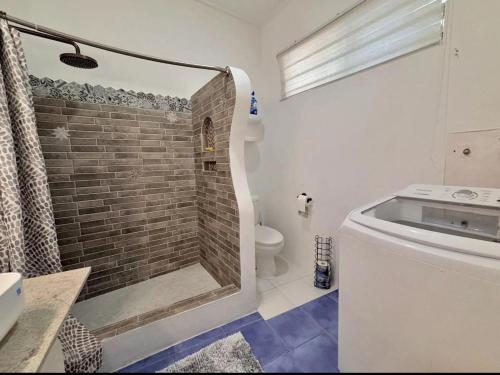 a bathroom with a walk in shower next to a toilet at Maple cottage in Bridgetown