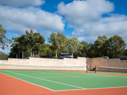 a tennis court with a bench on the court at Pullman Bunker Bay Resort Margaret River in Dunsborough