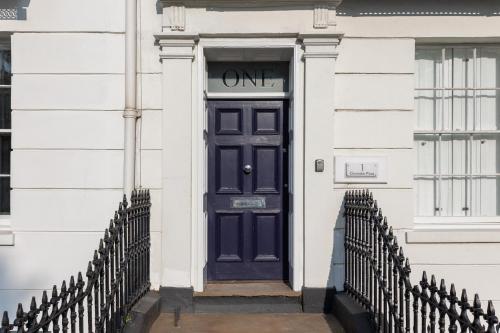 a blue door on a white building with a gate at Stylish 5-Bed Townhouse in Prime Leamington Spa in Leamington Spa