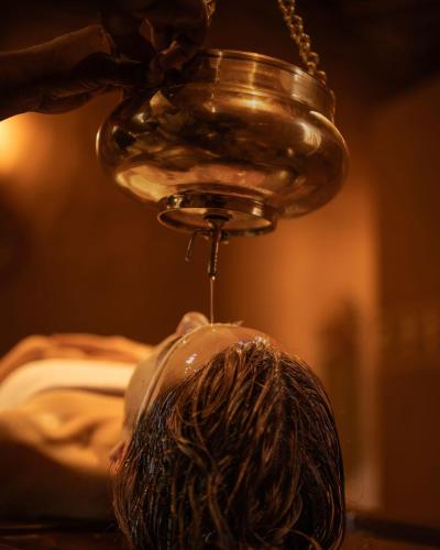 a man getting his hair washed under a glass jar at The Mudhouse Marayoor in Munnar