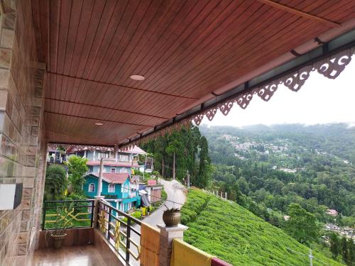 a balcony with a view of a green hill at The Garden View Family Homestay in Takdāh