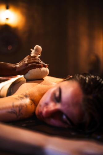 a woman laying in a bath tub with a figurine on her back at The Mudhouse Marayoor in Munnar