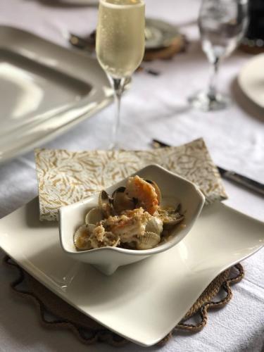 a bowl of food on a plate with a wine glass at La Pommeraie Champsecret, Lower Normandy in Champsecret