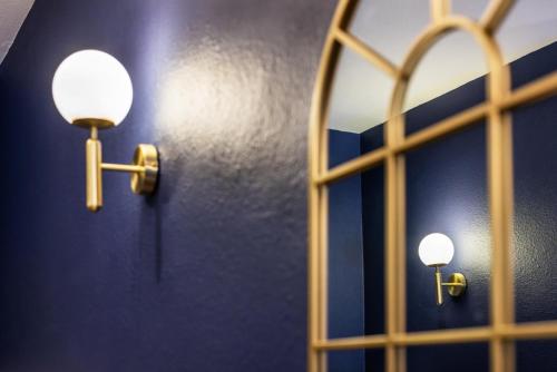 two lights on a blue wall with a mirror at Hotel Bristol Metz Centre Gare in Metz
