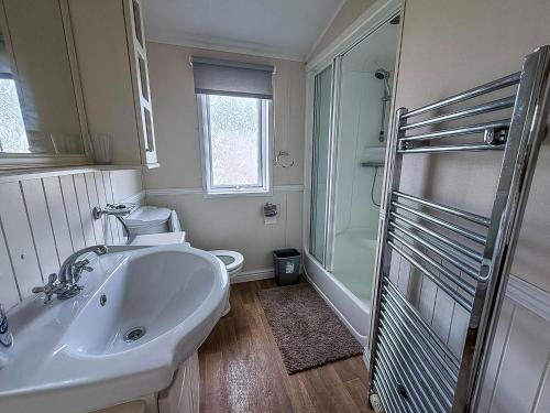 a white bathroom with a sink and a shower at 6 Berth Caravan For Hire At California Cliffs In Scratby By The Beach Ref 50050L in Great Yarmouth
