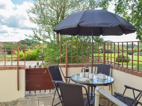 a table and chairs under an umbrella on a patio at Woodpecker Rest in Cilgerran