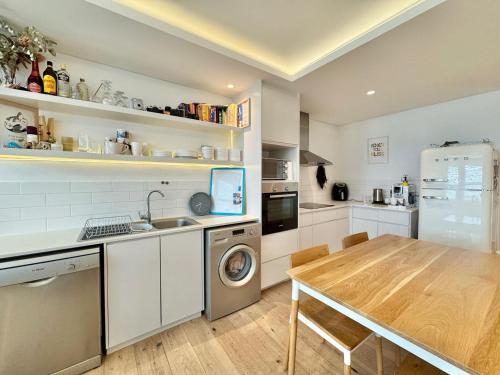 cocina con mesa, fregadero y nevera en Farmstyle Chic Designer Apartment, en Ciudad del Cabo