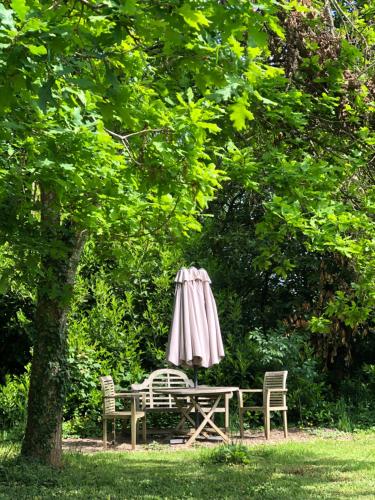 an umbrella and a table and chairs under a tree at La Pommeraie Champsecret, Lower Normandy in Champsecret