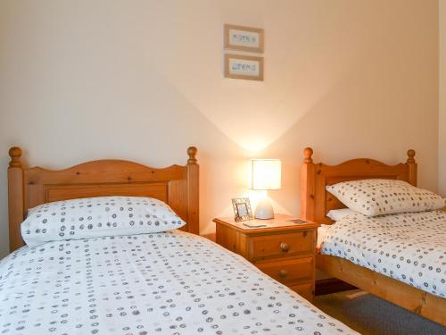 a bedroom with two beds and a table with a lamp at Beudy Mawr - 16985 in Brynsiencyn