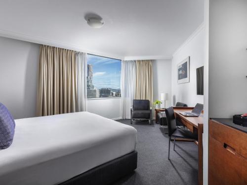 a hotel room with a bed and a desk and a computer at The Sebel Brisbane in Brisbane
