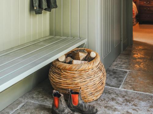 a basket filled with logs and boots next to a bench at The Shearing Shed in Peasmarsh