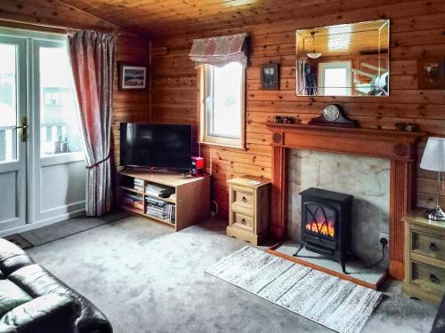 a living room with a fireplace and a tv at Bewick Lodge in Keswick