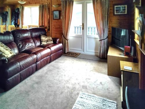 a living room with a leather couch and a television at Bewick Lodge in Keswick