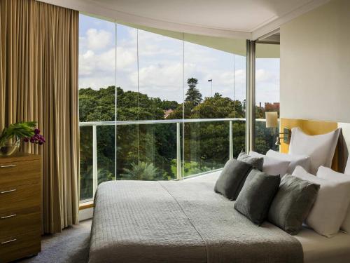 a bedroom with a bed with a large window at Pullman Quay Grand Sydney Harbour in Sydney