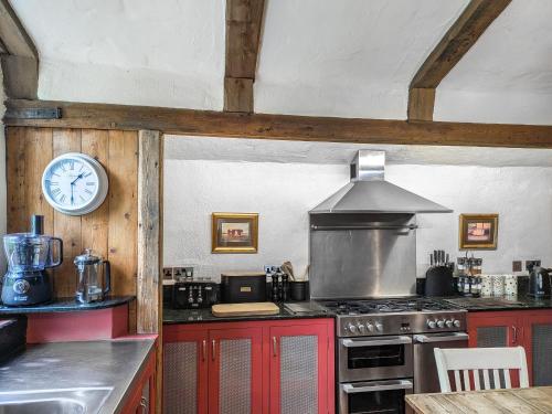 a kitchen with a stove and a clock on the wall at Stable End in Halesworth