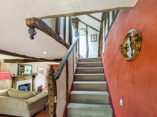 a staircase in a house with a red wall at Stable End in Halesworth