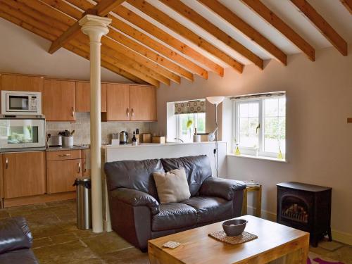 a living room with a leather couch and a table at Magpie Cottage in Gristhorpe