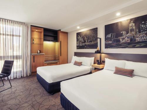 a hotel room with two beds and a chair at Mercure Brisbane King George Square in Brisbane