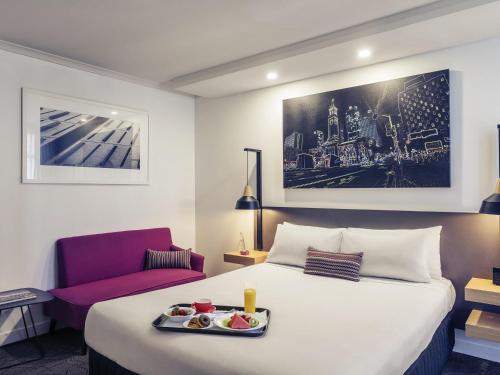 a hotel room with a bed with a tray of food on it at Mercure Brisbane King George Square in Brisbane