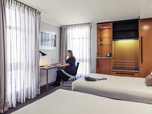 a woman sitting at a desk in a hotel room at Mercure Brisbane King George Square in Brisbane