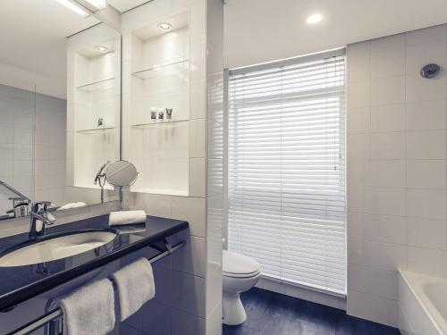 a white bathroom with a sink and a toilet at Mercure Brisbane King George Square in Brisbane