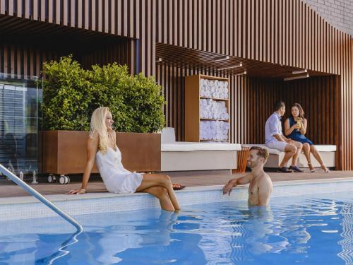 a man and a woman sitting in a swimming pool at Mercure Brisbane King George Square in Brisbane