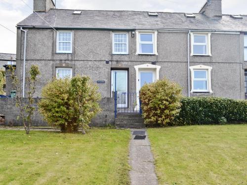 a gray brick house with a blue door at Minallt in Nefyn