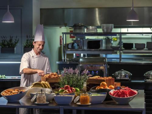 a chef standing in a kitchen with a table of food at Mercure Brisbane King George Square in Brisbane