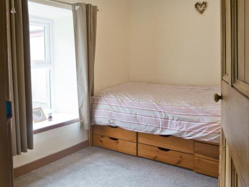 a small bedroom with a bed and a window at Minallt in Nefyn