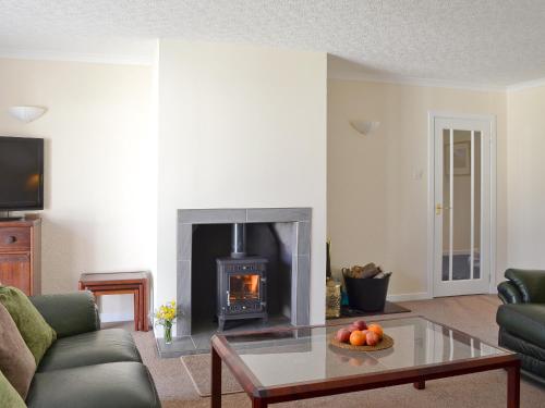 a living room with a fireplace and a coffee table at Tall Pines in Carrbridge
