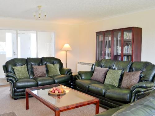 a living room with leather couches and a coffee table at Tall Pines in Carrbridge