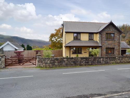 a yellow house with a stone wall and a fence at Ty Glyndwr in Ystalyfera