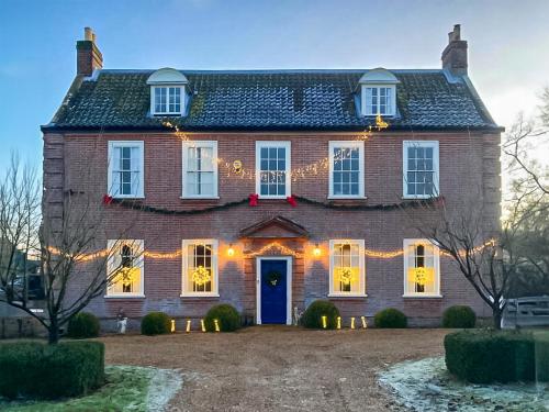 a large brick house with christmas lights on it at Hemblington Hall Arts And Leisure Ltd in South Walsham