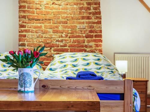 a bed with a vase of flowers on a wooden table at Hemblington Hall Arts And Leisure Ltd in South Walsham