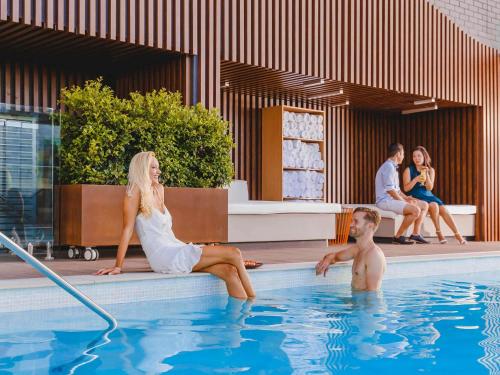 a woman in a white dress sitting in a swimming pool at Pullman Brisbane King George Square in Brisbane