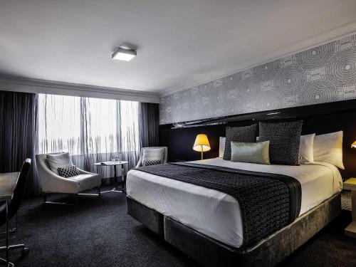 a hotel room with a large bed and a chair at Pullman Brisbane King George Square in Brisbane