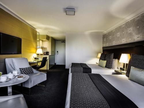 a hotel room with a bed and a living room at Pullman Brisbane King George Square in Brisbane