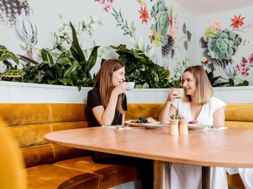 two women sitting at a table drinking coffee at Pullman Brisbane King George Square in Brisbane