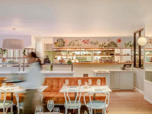 a person walking through a restaurant with tables and chairs at Pullman Brisbane King George Square in Brisbane