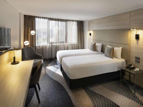 a hotel room with a large bed and a television at Novotel Sydney Parramatta in Sydney