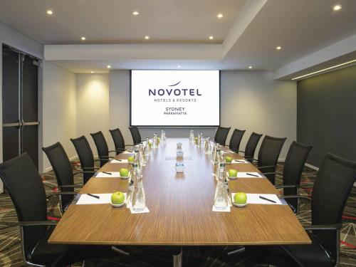 a long table in a room with chairs and a screen at Novotel Sydney Parramatta in Sydney