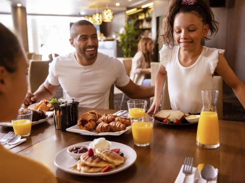 a group of people sitting around a table eating breakfast at Novotel Sydney Parramatta in Sydney