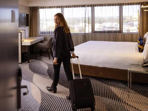 a woman with a suitcase in a hotel room at Novotel Sydney Parramatta in Sydney