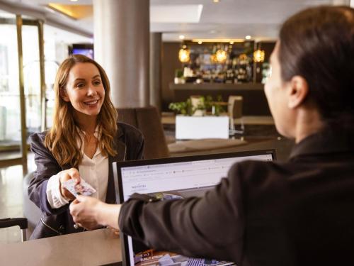 two women sitting at a table in a restaurant shaking hands at Novotel Sydney Parramatta in Sydney