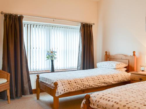 a bedroom with two beds and a large window at Beudy Mawr - 16985 in Brynsiencyn