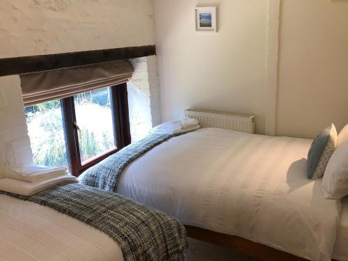 a bedroom with two beds and a window at Cider Press Cottage in Fowey