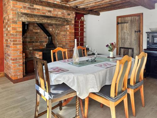 a dining room with a table with chairs and a fireplace at Field Cottage in Sudbourne