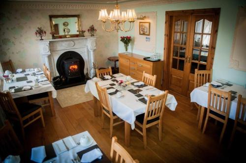 a dining room with two tables and a fireplace at The Old Parochial House in Speenoge