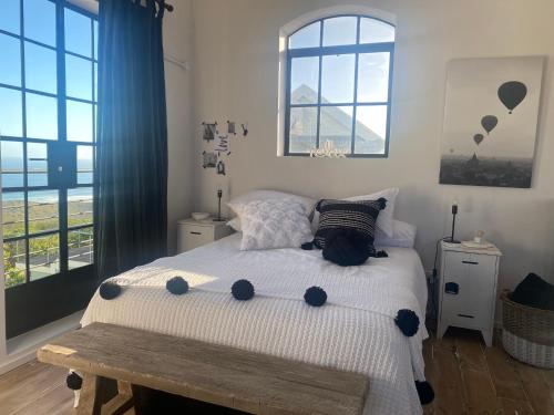 a bedroom with a bed and two windows at Bellamore - Stylish Loft Studio with Sea Views in Brenton-on-Sea